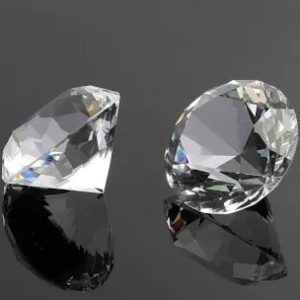 Zwei klare Diamanten auf einer reflektierenden schwarzen Oberfläche.