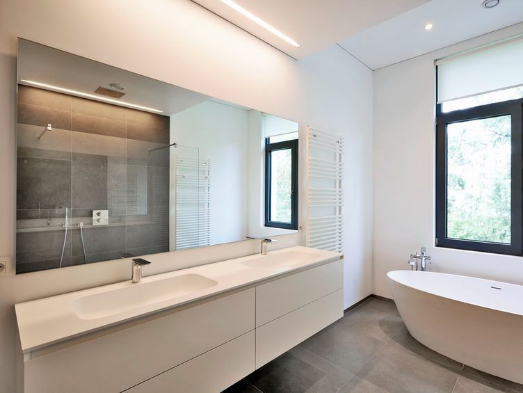 Un baño con dos lavabos, una bañera y un espejo grande.