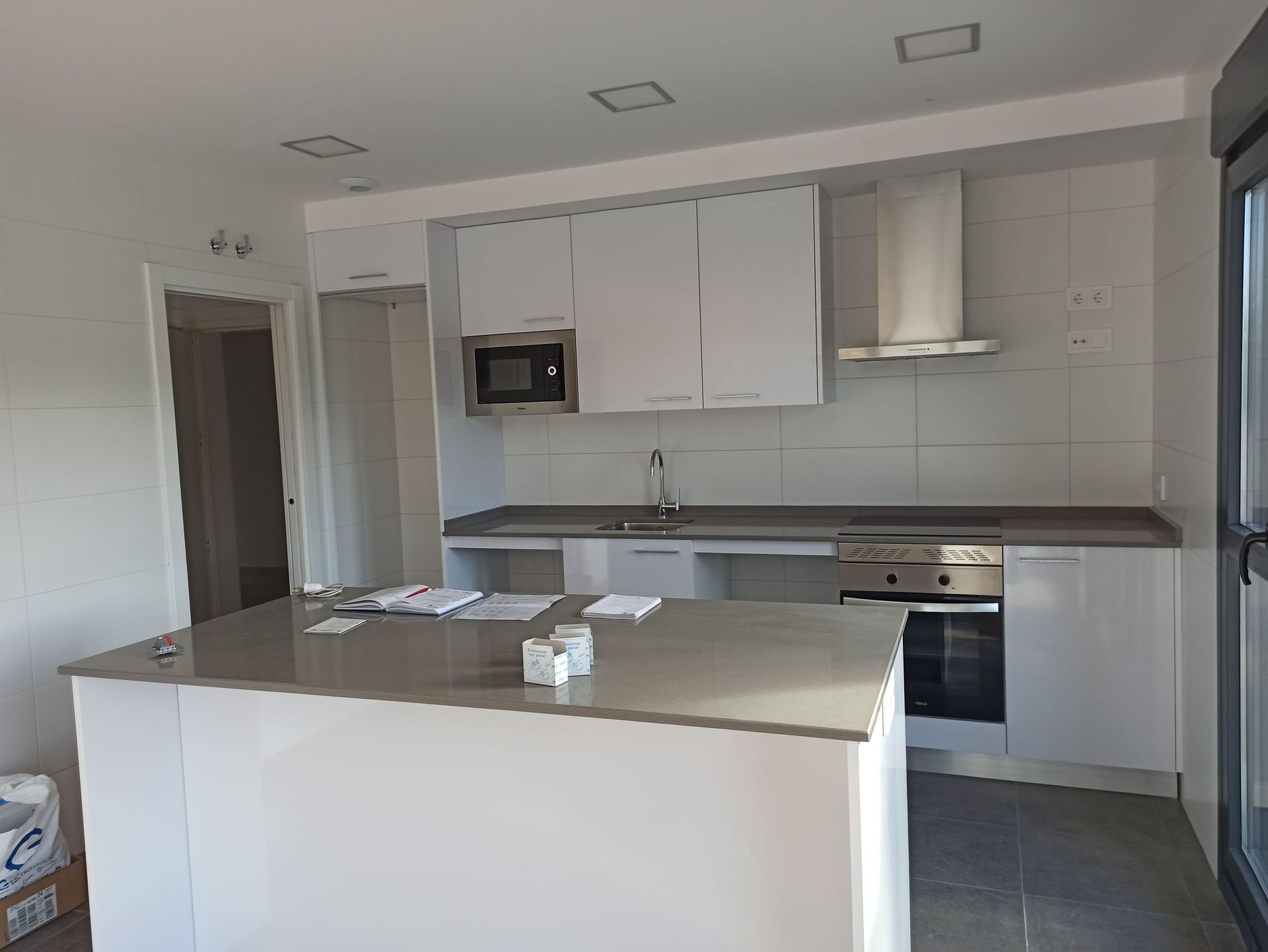 Una cocina con gabinetes blancos y electrodomésticos de acero inoxidable.