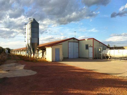 Un gran edificio blanco con un silo delante.