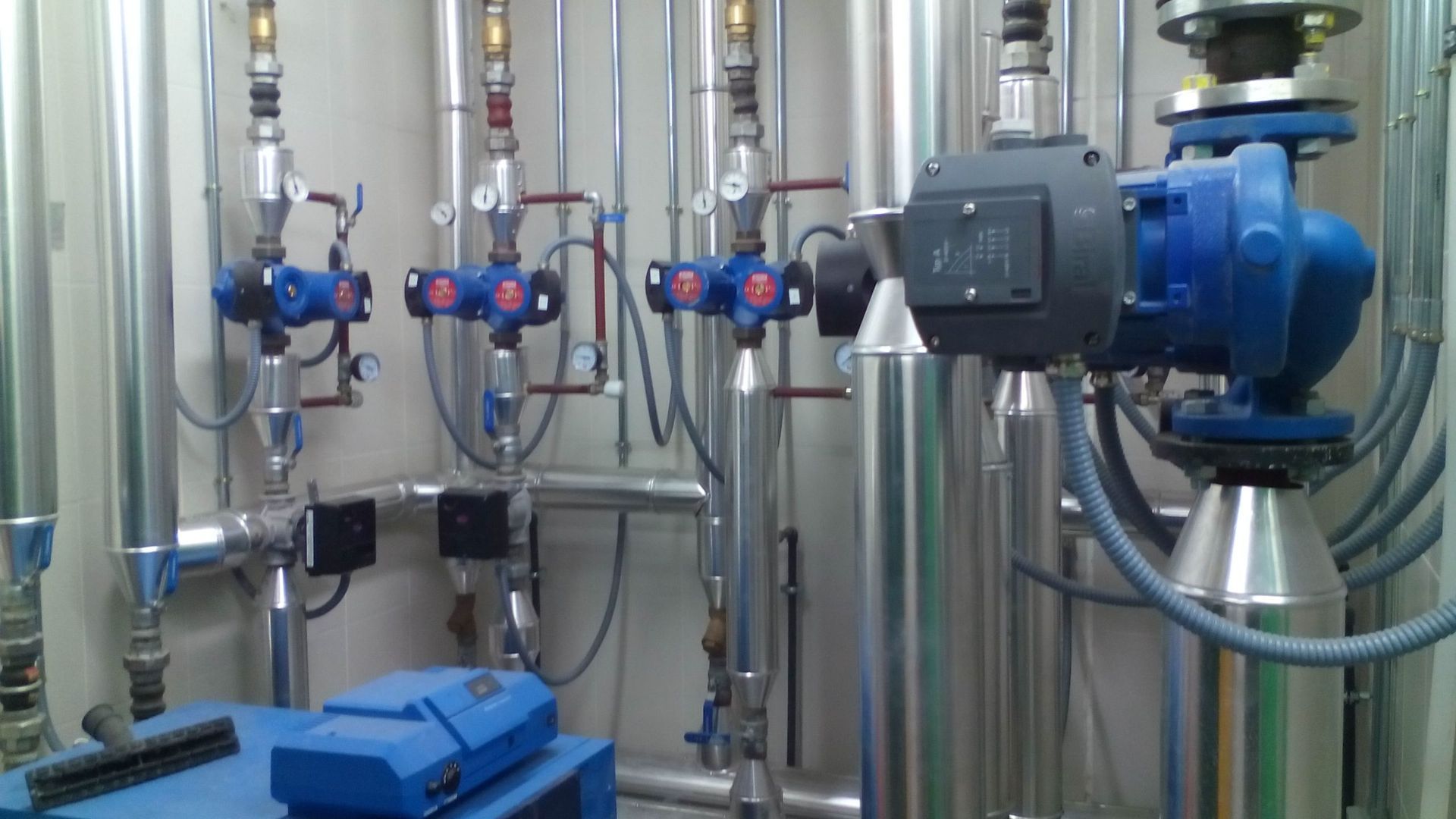 Una habitación llena de muchas tuberías y una máquina azul.