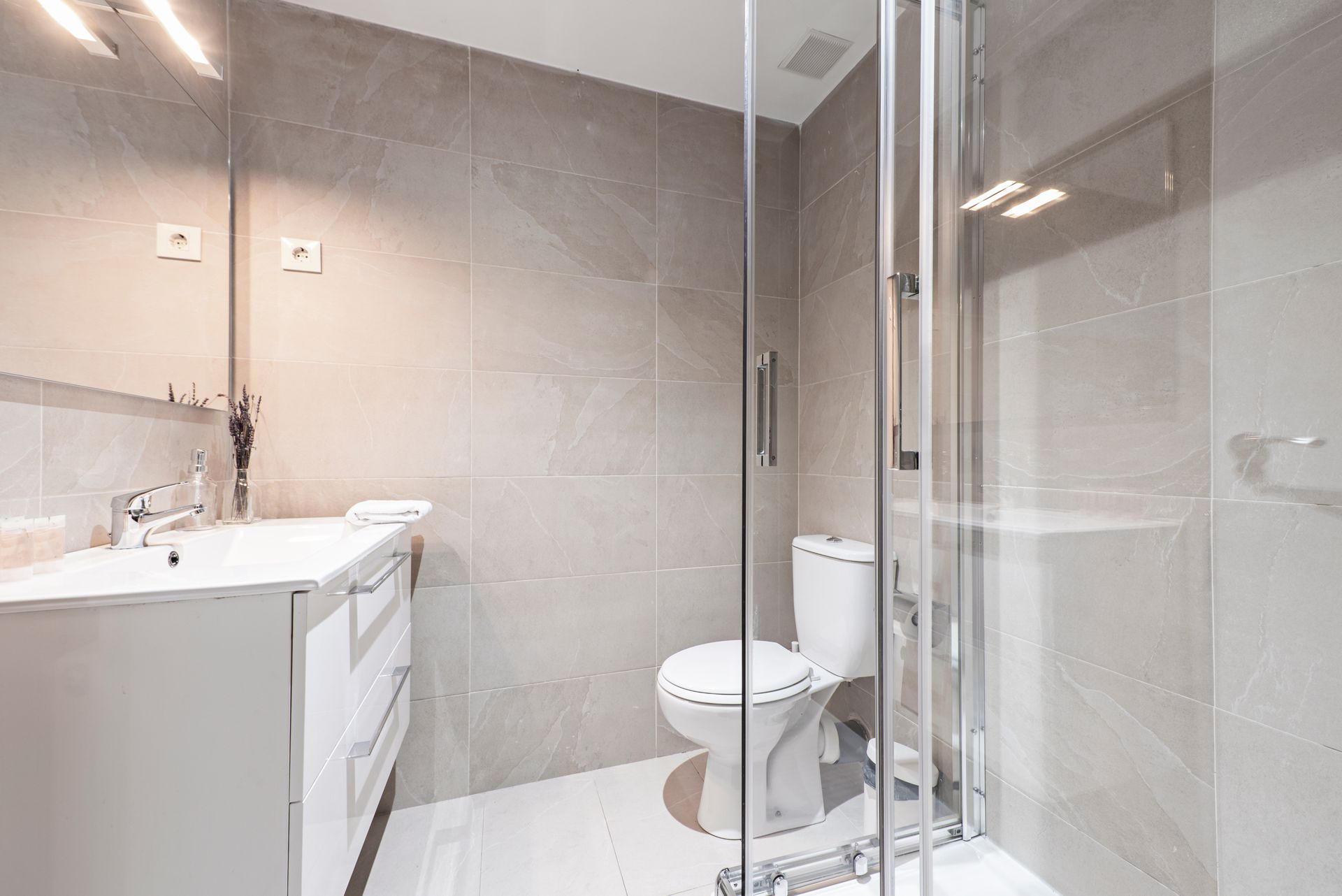Badezimmer mit ebenerdiger Dusche, helle Fliesen