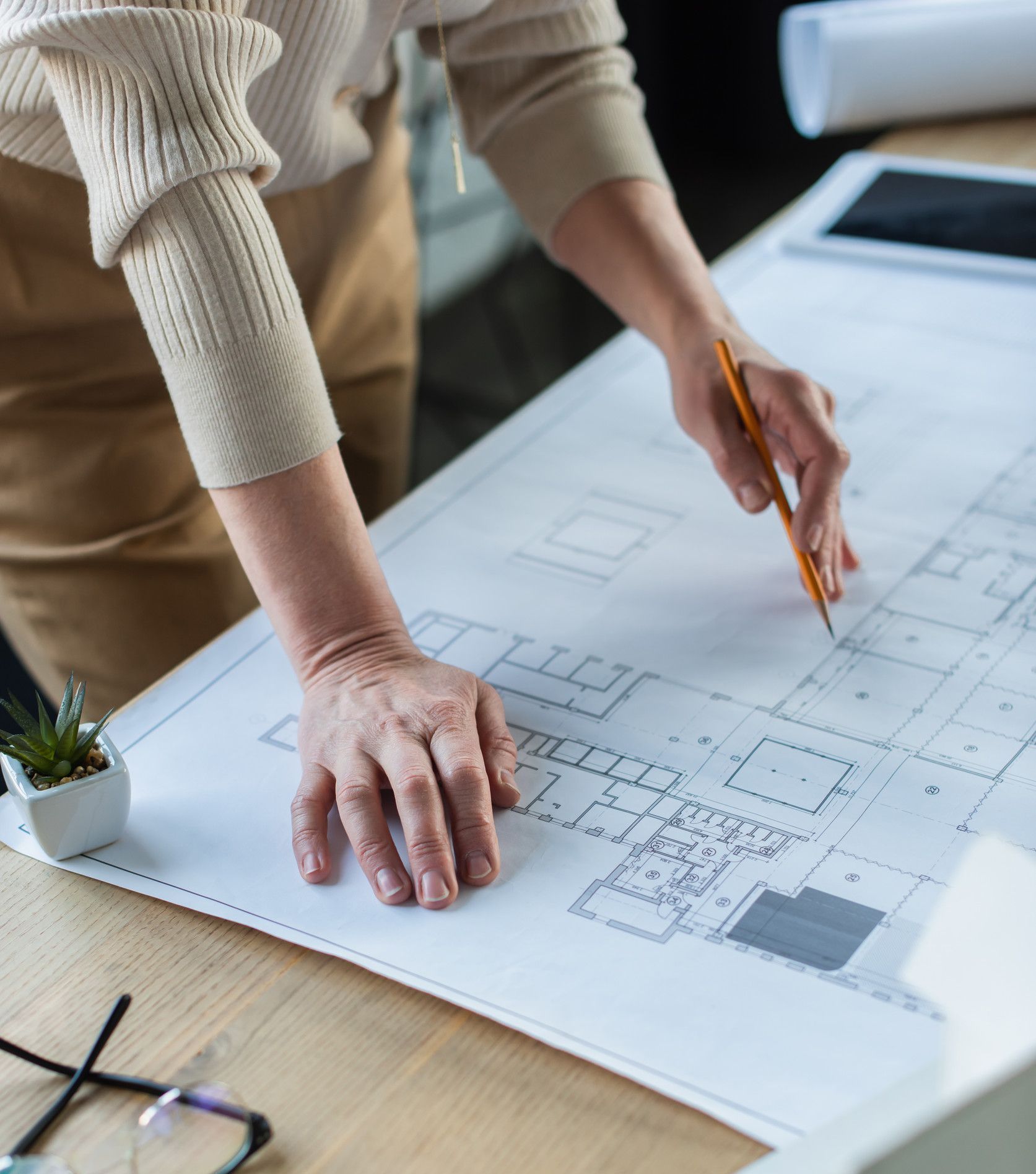Una mujer está trabajando en un plano con un lápiz.