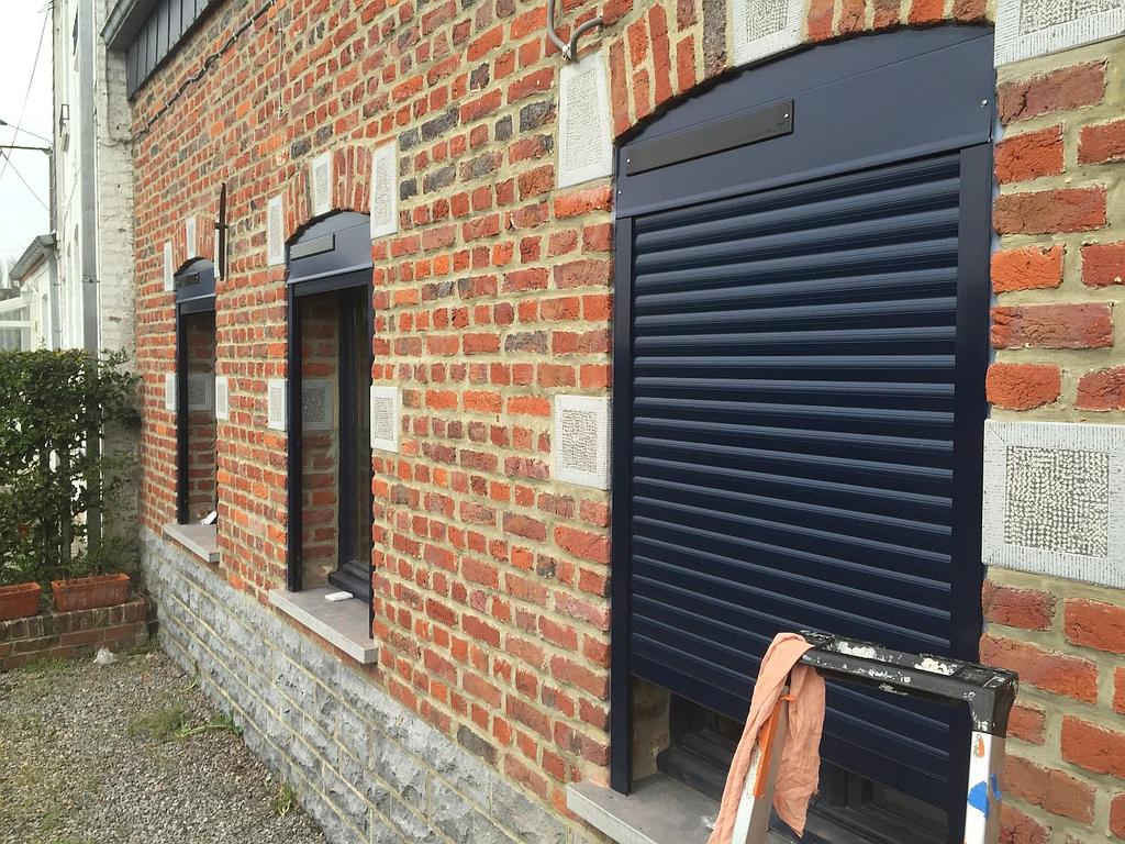 Façade d'une maison en brique avec 3 fenêtres noires
