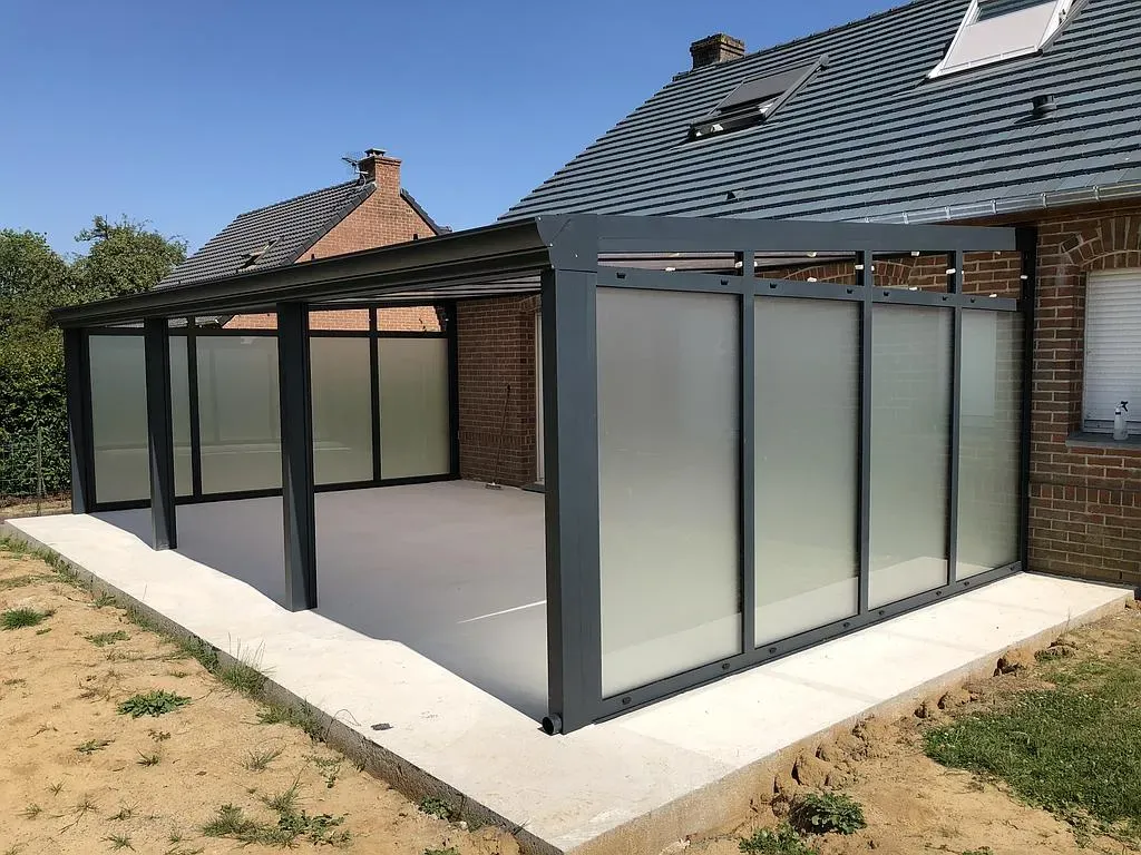 Grande véranda gris foncé avec vitres opaques dans le jardin d'un maison en brique