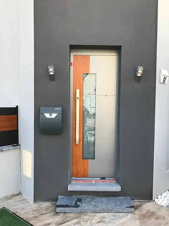 Porte d'entrée mi-argentée mi-bois avec une grande poignée dorée