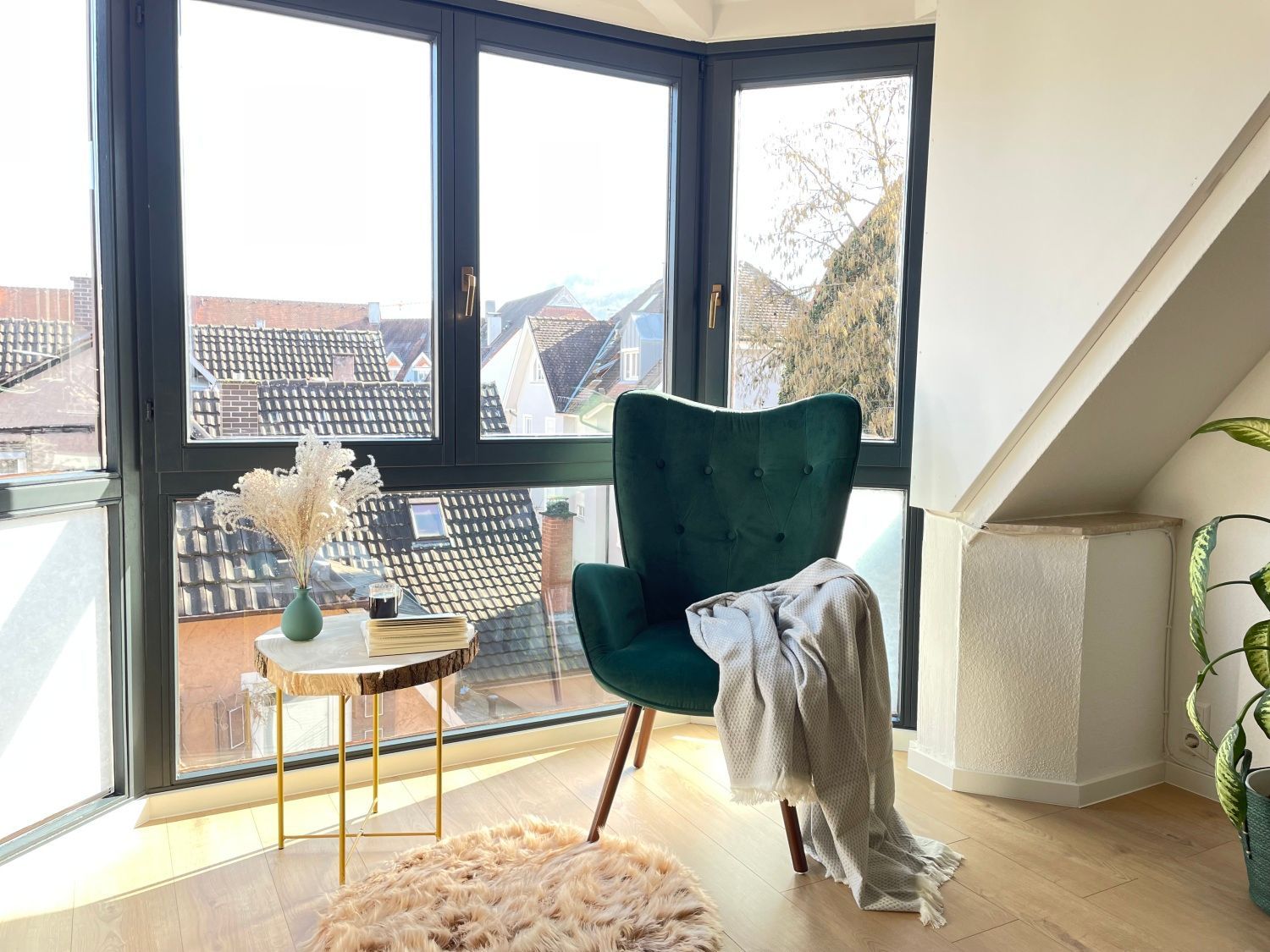 Grüner Sessel mit Tagesdecke und Beistelltisch am großen Fenster mit Aussicht