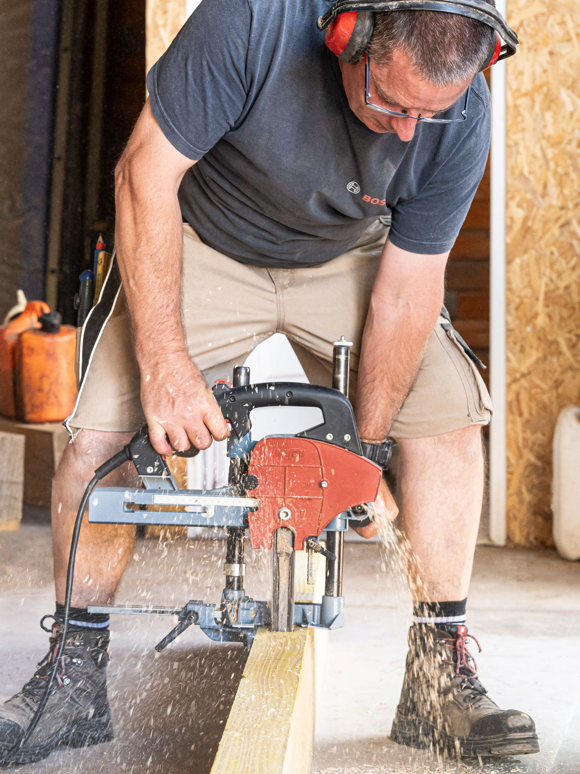 Un charpentier coupe une poutre avec une scie circulaire