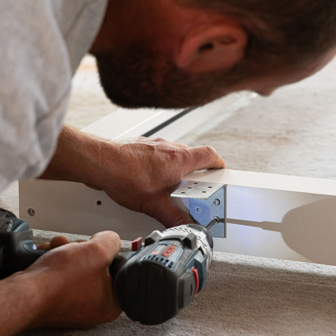 Gros plan d'un artisan avec une visseuse sur un cadre de fenêtre double vitrage