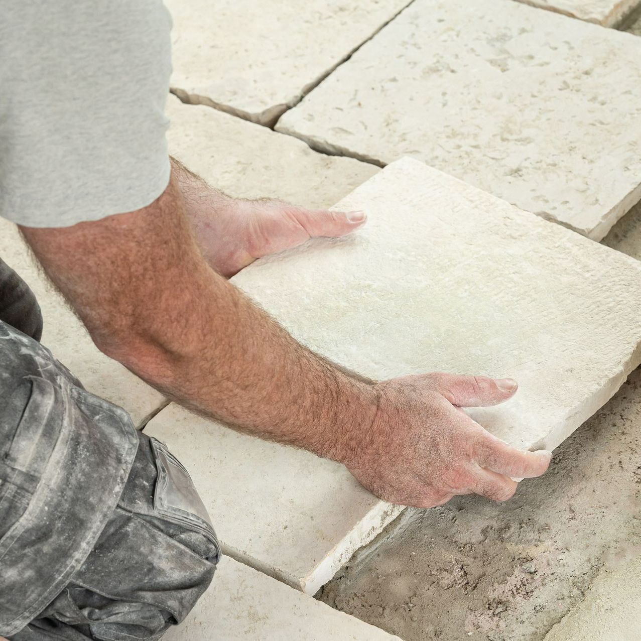 Gros plan sur les mains d'un carleur qui pose une dalle beige