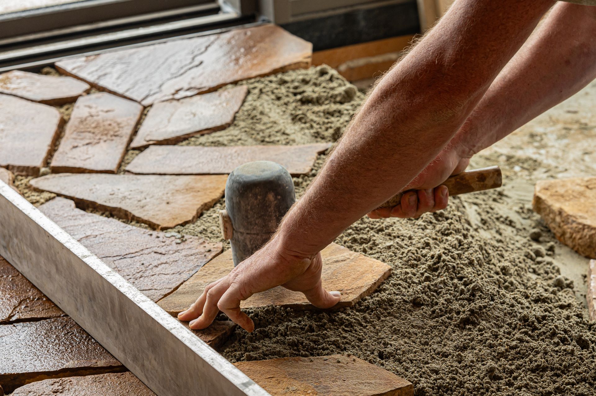Gros plan sur les mains d'un artisan carleur qui pose des carreaux aux formes variées