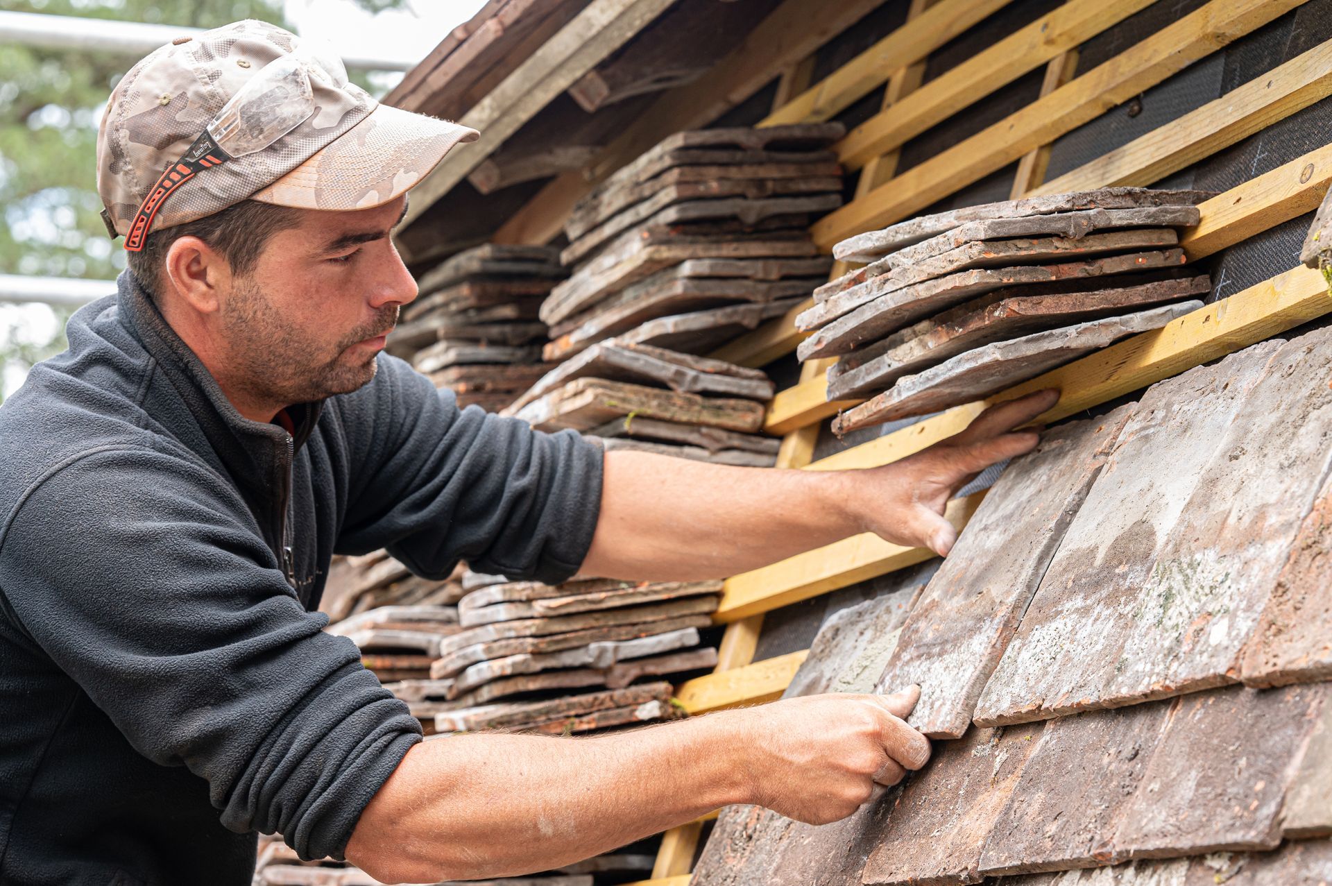 Un ouvrier pose des tuiles sur la charpente d'un toit