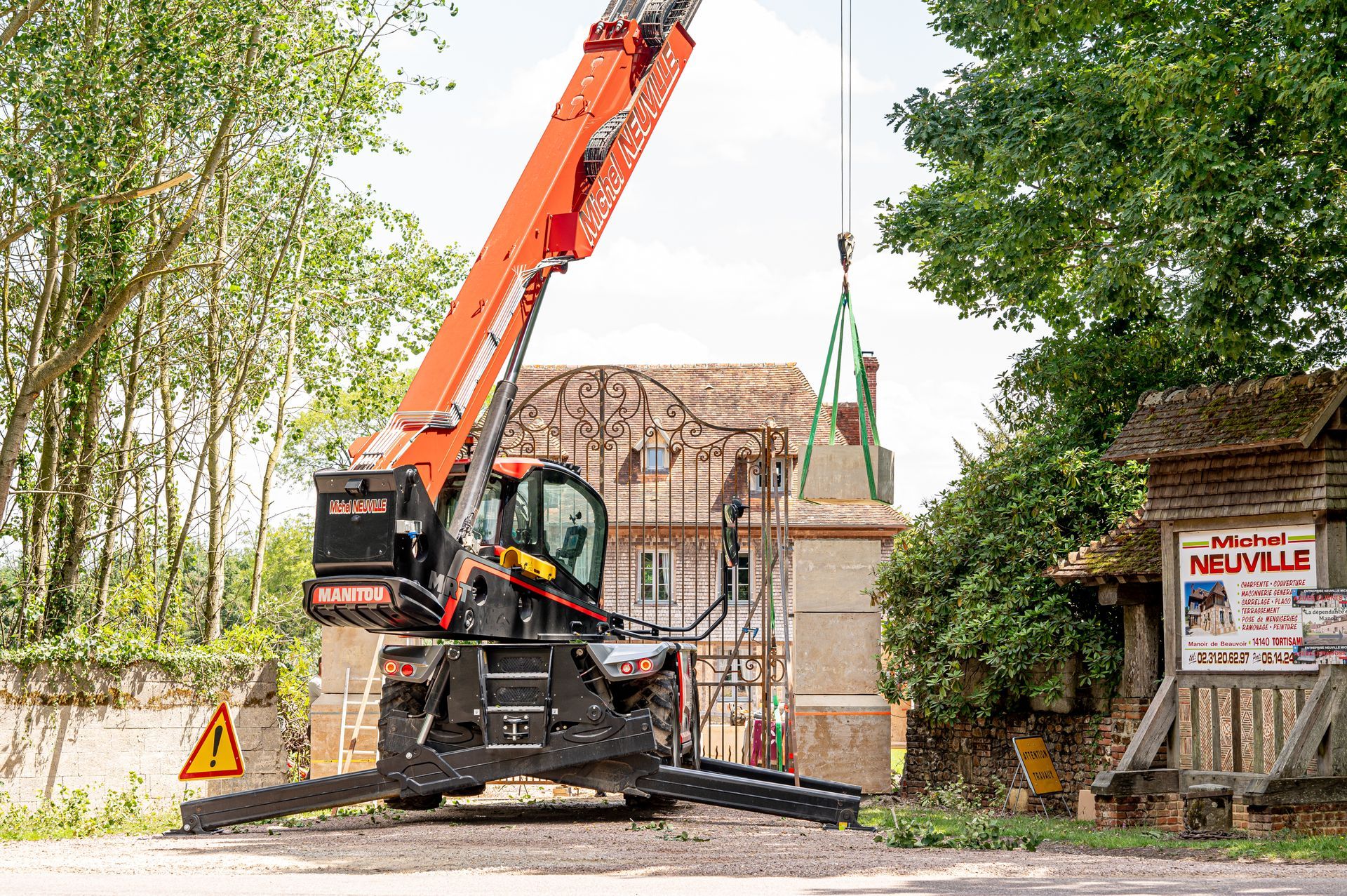 Pierres de taille soulever par un engin de chantier devant le portail d'une maison ancienne
