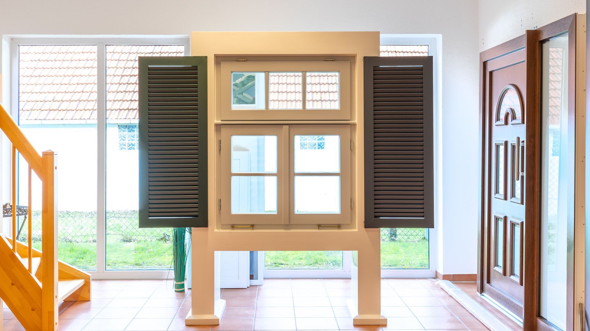 Ein Raum mit einer Treppe und einem Fenster mit Fensterläden