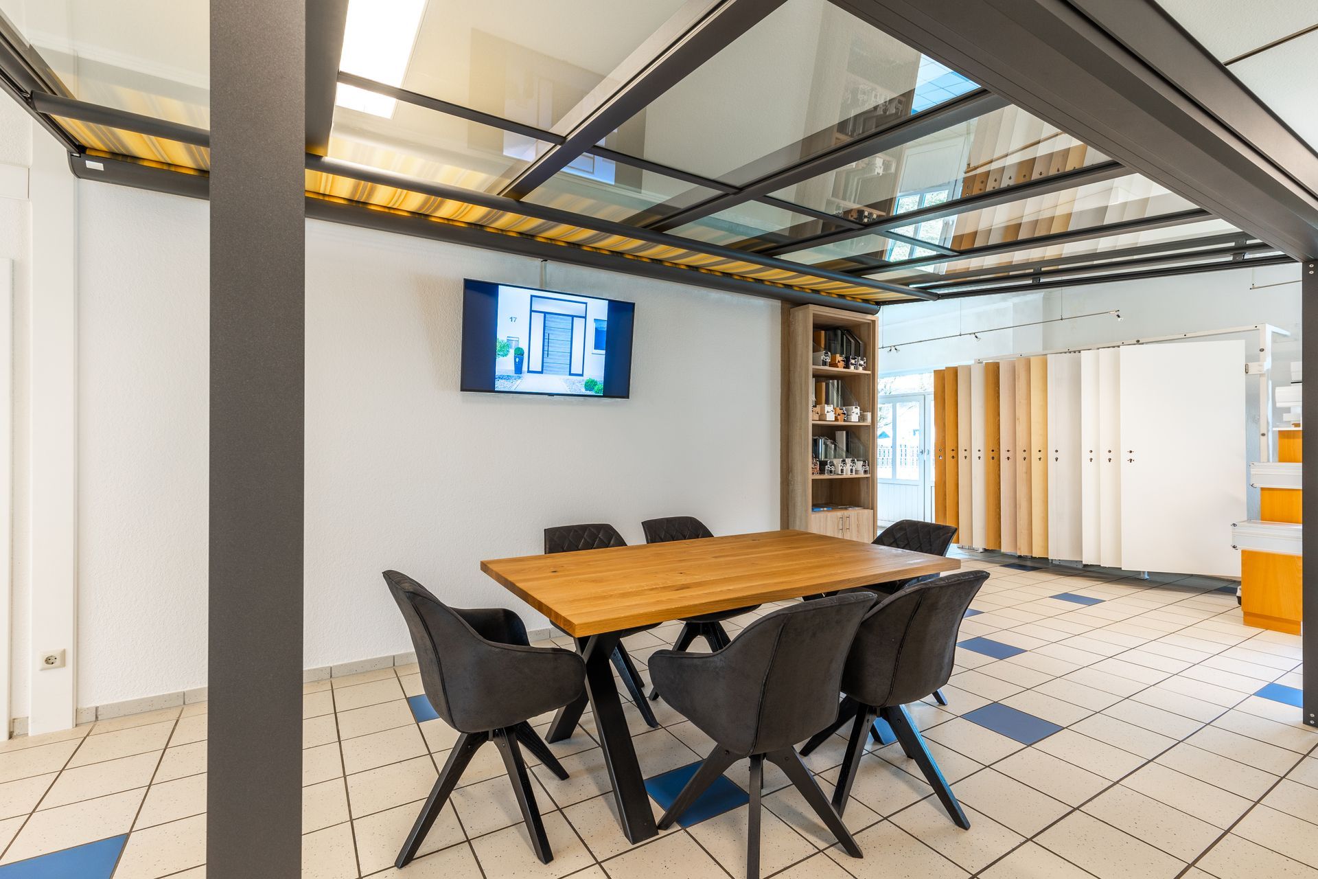 Ein Konferenzraum mit einem Tisch und Stühlen und einem Fernseher an der Wand.