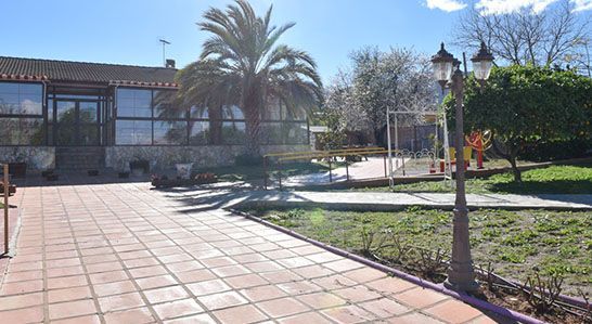 Una pasarela de ladrillos que conduce a una casa grande con palmeras al fondo.