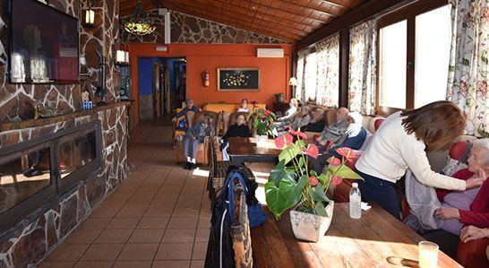 Un grupo de personas están sentadas en mesas en una habitación con chimenea.
