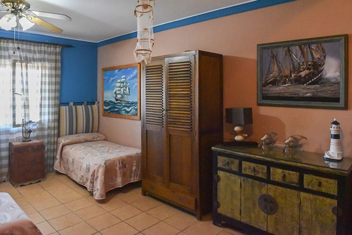 Un dormitorio con dos camas, una cómoda, un faro y un ventilador de techo.
