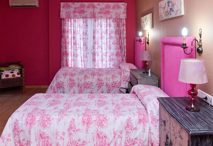Un dormitorio con dos camas y un cabecero rosa.