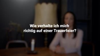 Eine Frau sitzt an einem Tisch. Im Hintergrund ist eine Lampe zu sehen.