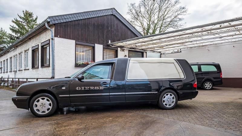 Vor einem Gebäude parkt ein Leichenwagen.