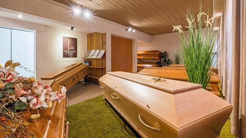 Ein Raum voller Särge und Blumen in einem Bestattungsinstitut.