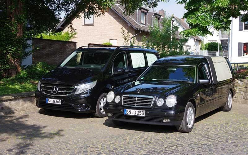 Zwei schwarze Autos parken nebeneinander auf einer Kopfsteinpflasterstraße.