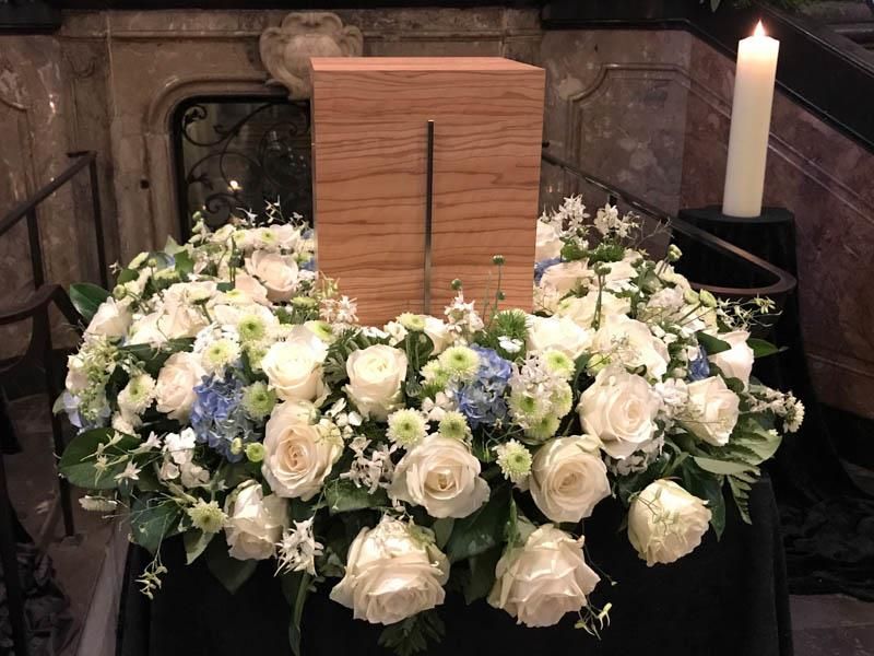 Eine Holzkiste ist von Blumen und einer Kerze umgeben