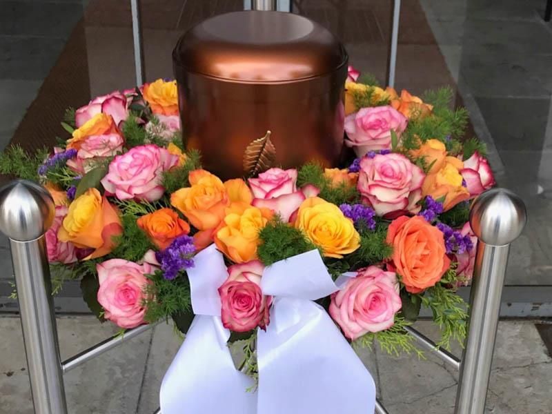 Eine Urne ist von einem Blumenkranz umgeben