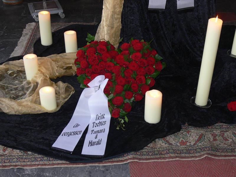 Ein Herz aus roten Rosen ist von Kerzen umgeben