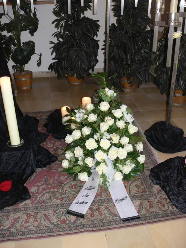 Ein Strauß weißer Rosen liegt auf einem Teppich neben Kerzen