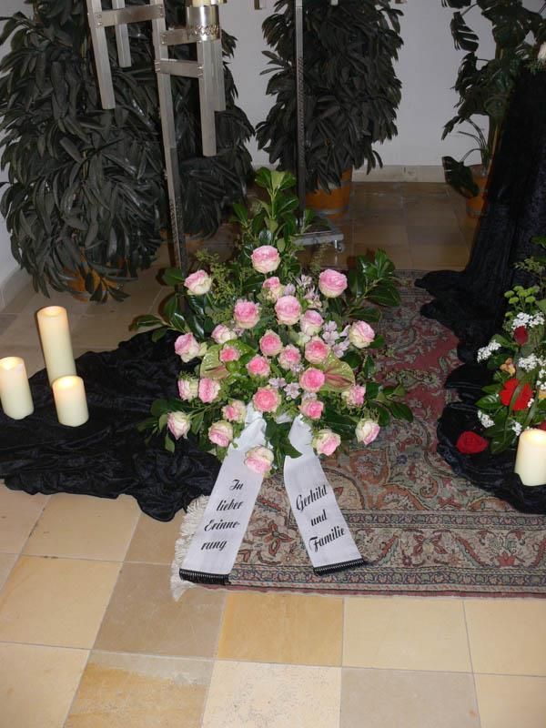 Ein Strauß rosa Rosen liegt auf einem Teppich mit Kerzen