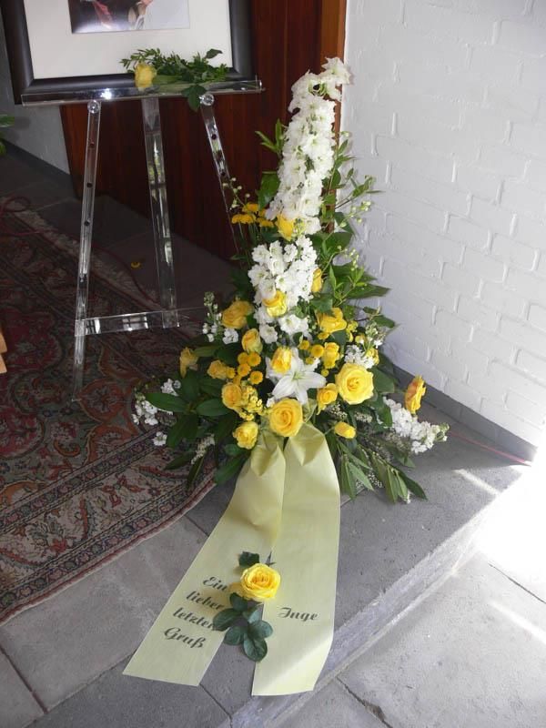 Ein Strauß gelber und weißer Blumen mit einer gelben Schleife