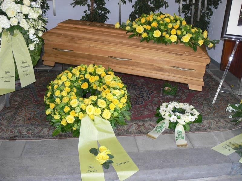 Ein Holzsarg mit gelben und weißen Blumen darauf