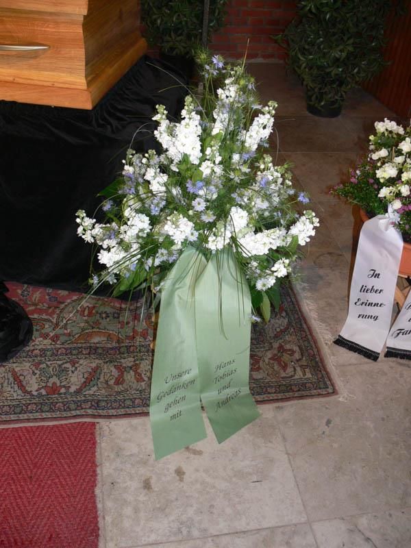 Ein Strauß weißer und blauer Blumen mit einer grünen Schleife