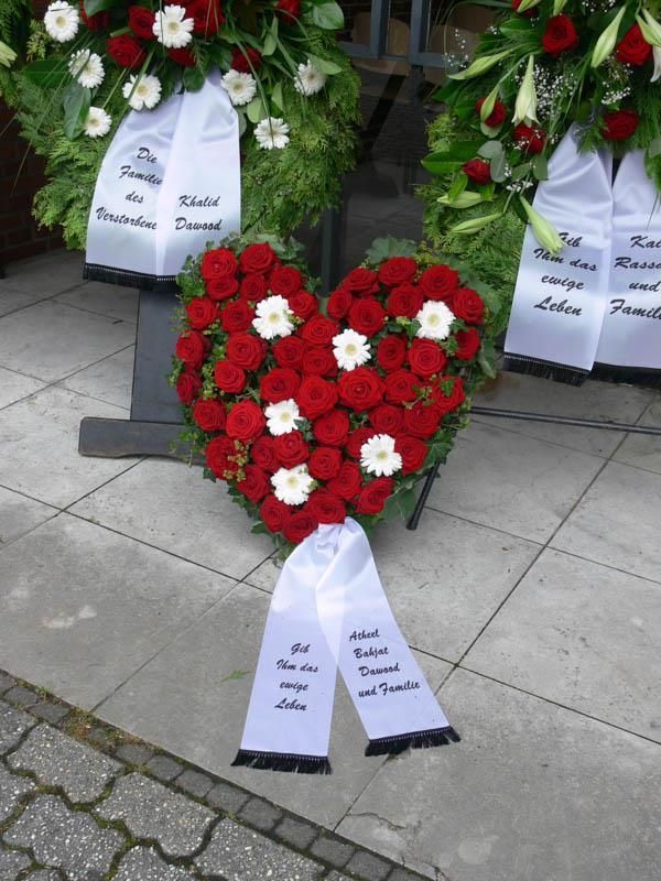 Ein herzförmiger Kranz mit roten Rosen und weißen Gänseblümchen