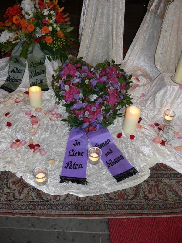 Ein herzförmiger Kranz mit einem lila Band, auf dem steht „in Liebe Petra“