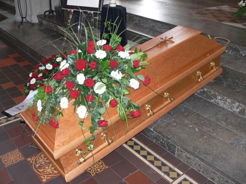 Ein Holzsarg mit roten und weißen Blumen darauf