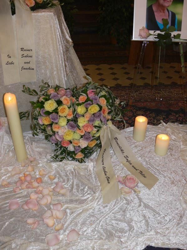 Ein herzförmiger Blumenstrauß steht auf einem Tisch mit Kerzen