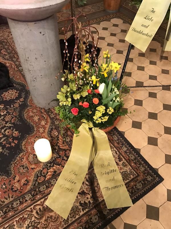 Eine Vase mit Blumen steht auf einem Teppich neben einer Kerze
