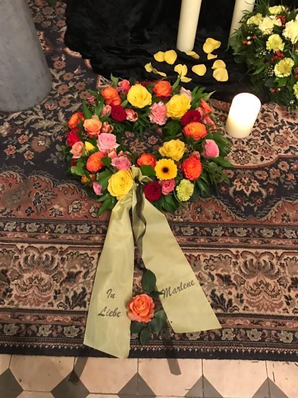 Ein Blumenkranz liegt auf einem Teppich neben einer Kerze