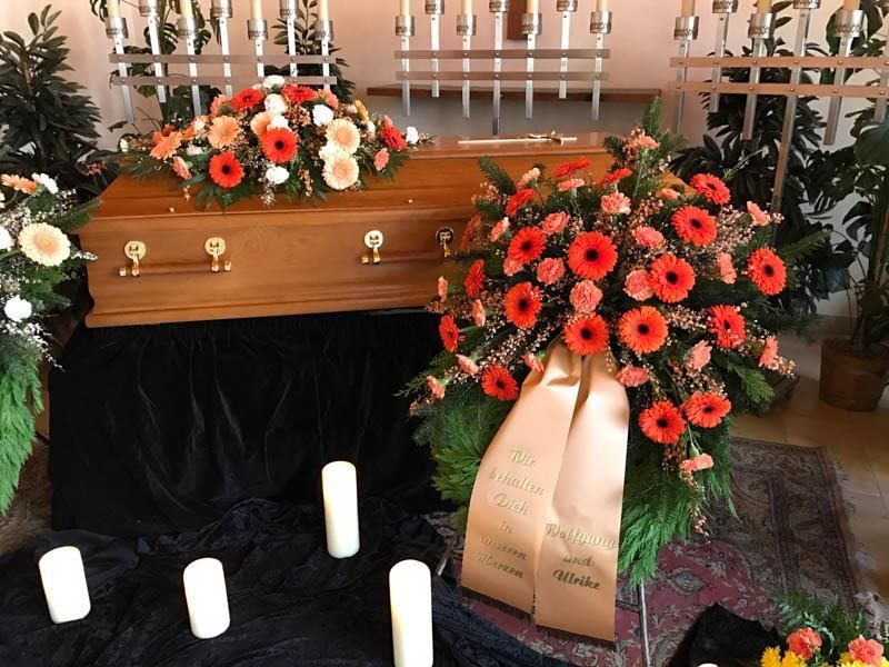 Ein Sarg mit Blumen und Kerzen davor