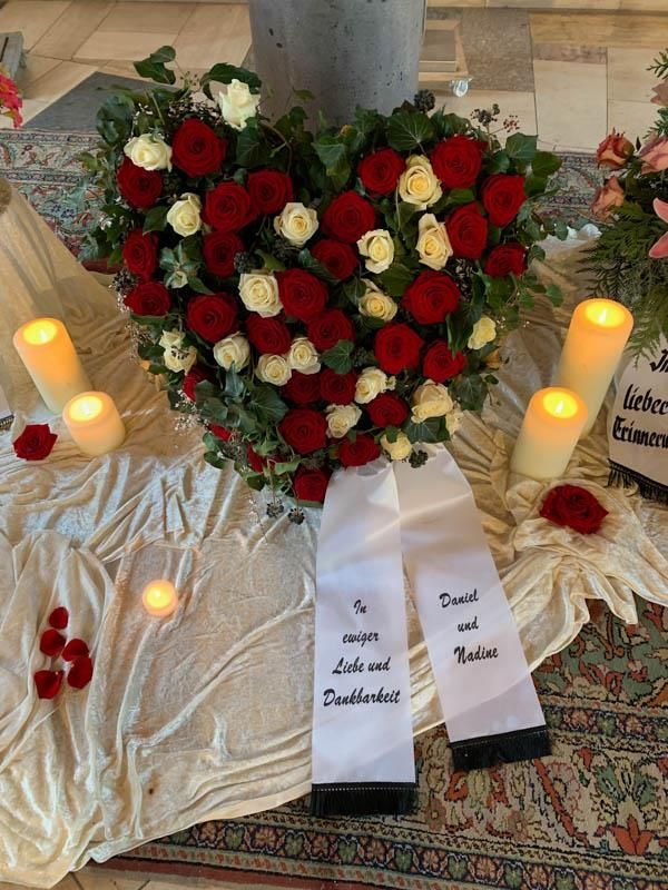 Ein Herz aus roten und weißen Rosen mit Kerzen darum herum