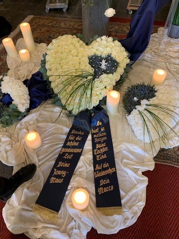 Ein Herz aus weißen Blumen mit einem Kreuz darauf