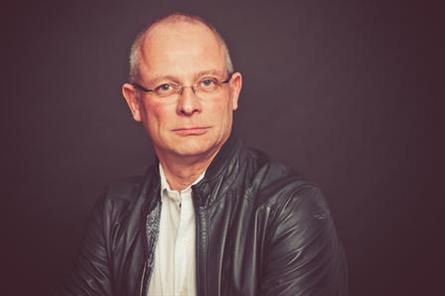 Ein Mann mit Brille und Lederjacke schaut in die Kamera.