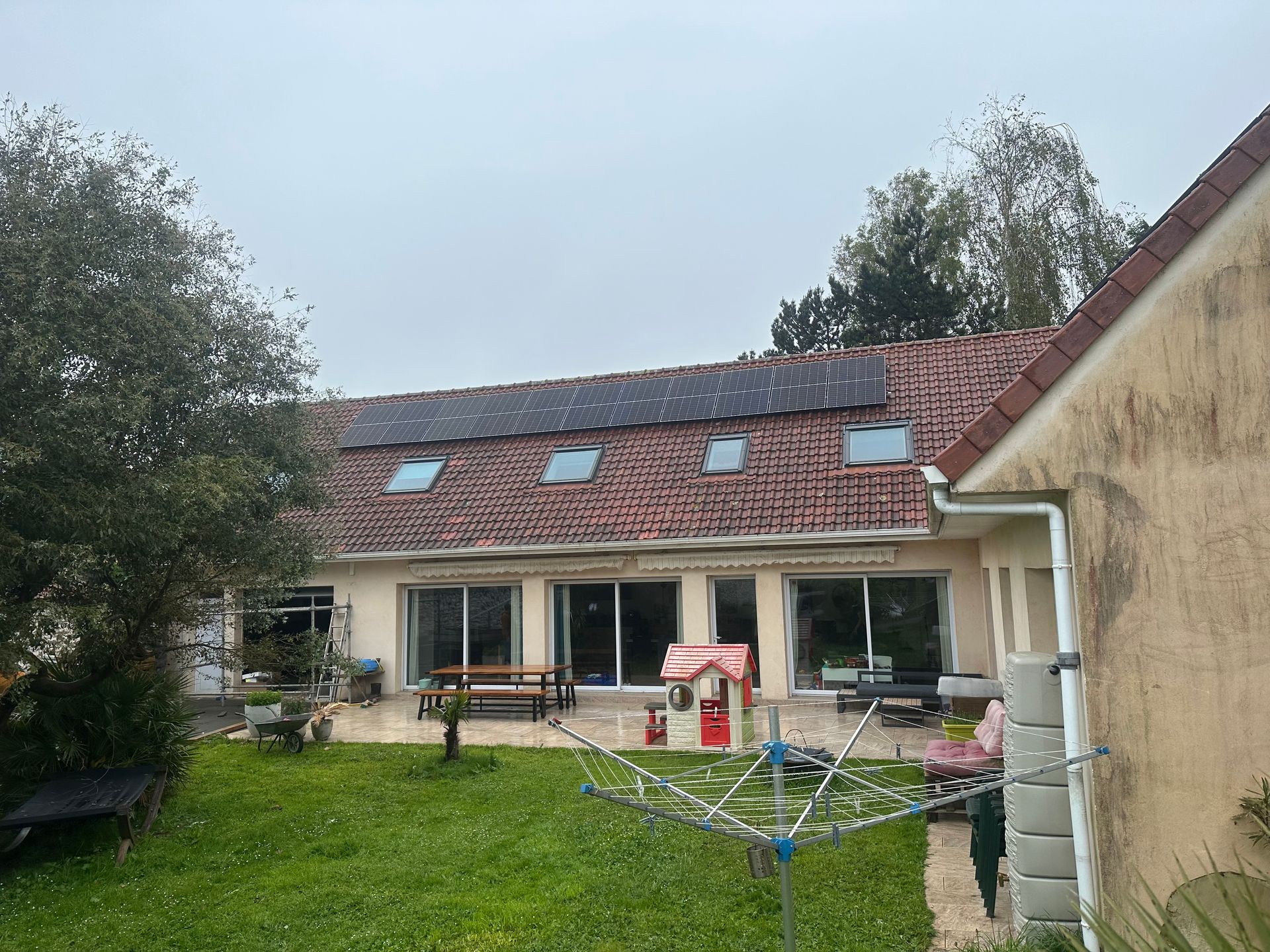 Maison avec une toiture composée de fenêtres de toit et de panneaux solaires
