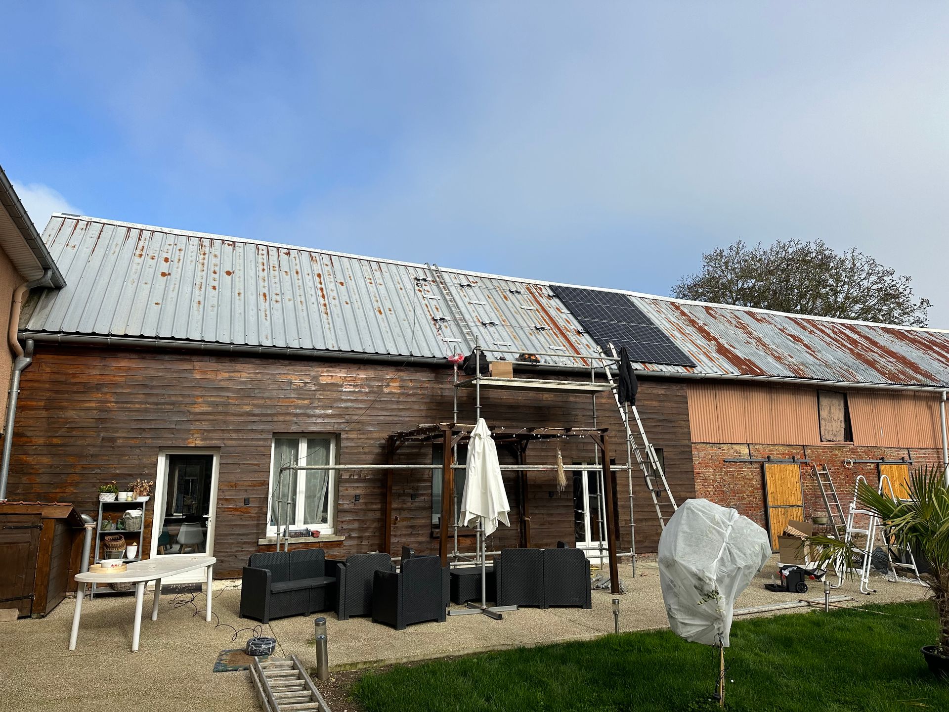 Échafaudage devant une maison avec un bardage en bois et une toiture en zinc