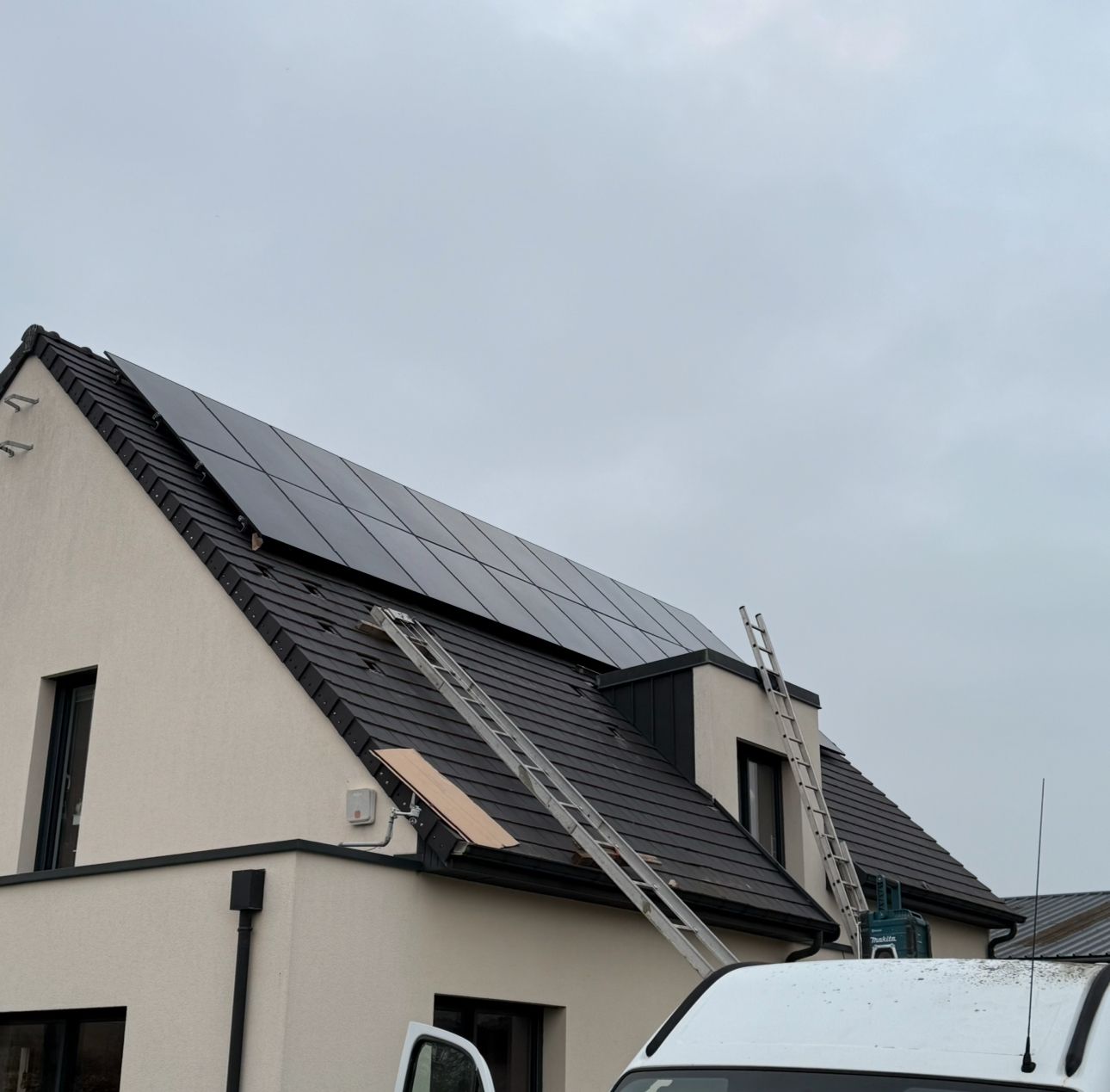 Maison avec des panneaux solaires sur le toit et deux échelles