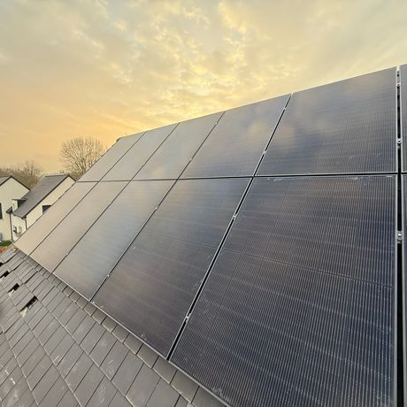 Panneaux solaires foncés sur un toit en ardoise en fin de journée