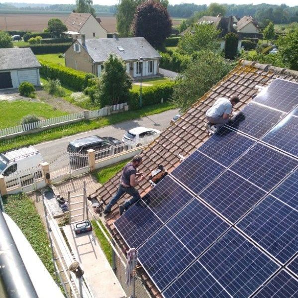 Deux hommes sur la toiture d'une maison en train de poser des panneaux solaires